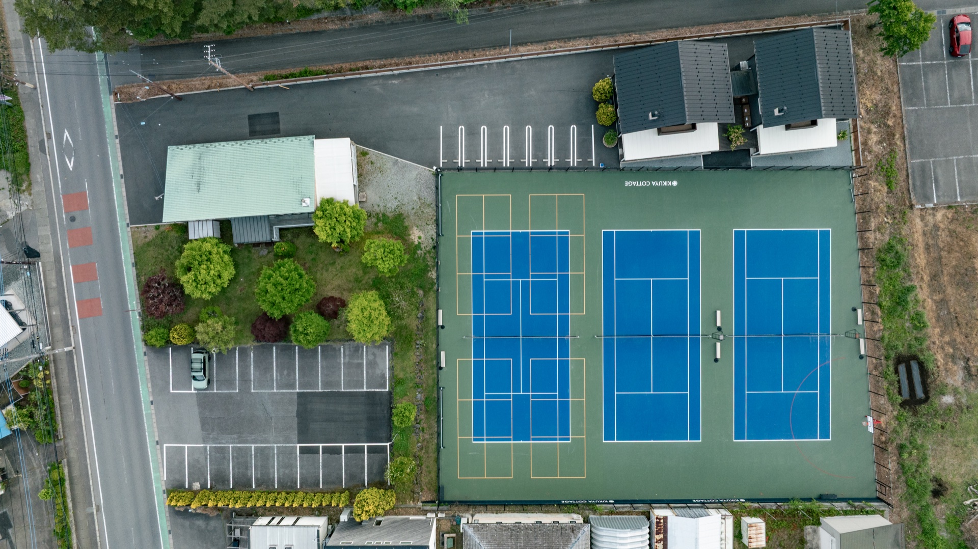 Aerial view of cottages, parking, and tennis courts